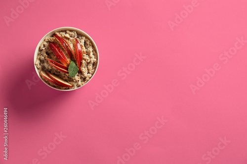 Bowl with tasty sweet oatmeal on color background