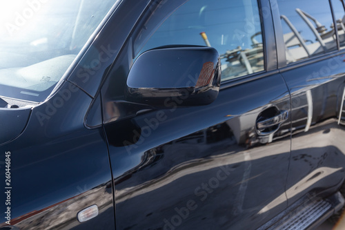 Side mirror view of car in black color after cleaning before sale in a sunny day on parking © Aleksandr Kondratov