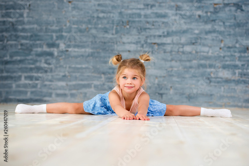 Little girl is sitting on a string. Young girls doing gymnastics.
