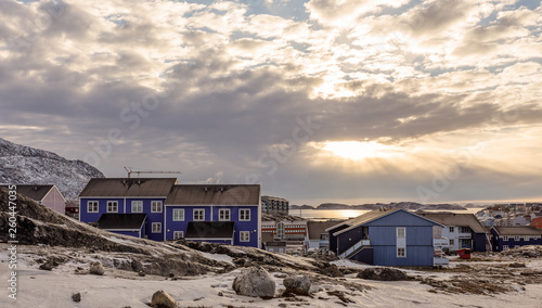 Polar sunset over Inuit houses on the rocky hills with snow, Nuuk city, Greenland