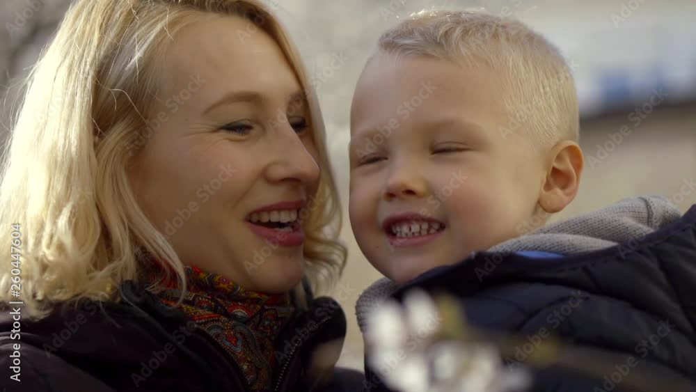 Beautiful outdoor portrait of charming blonde middle aged mother holding her little blonde son. Beautiful outdoor portrait of charming blonde middle aged mother holding her little blonde son.
