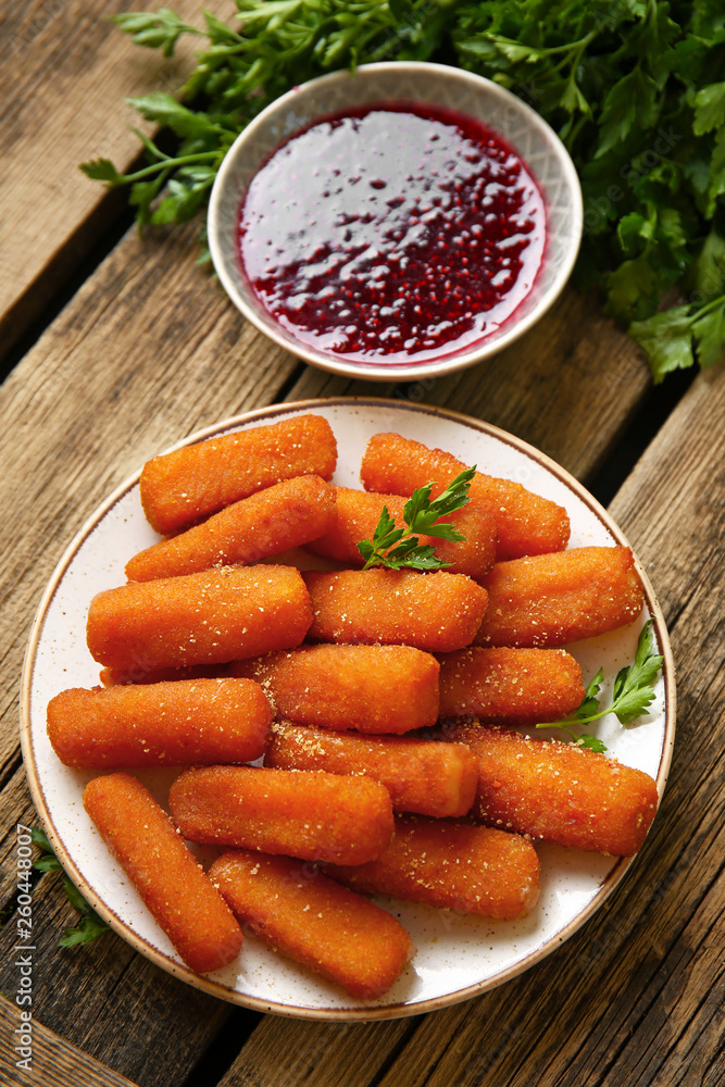Plate with tasty mozzarella sticks and jam on wooden table Plate with tasty mozzarella sticks and jam on wooden table