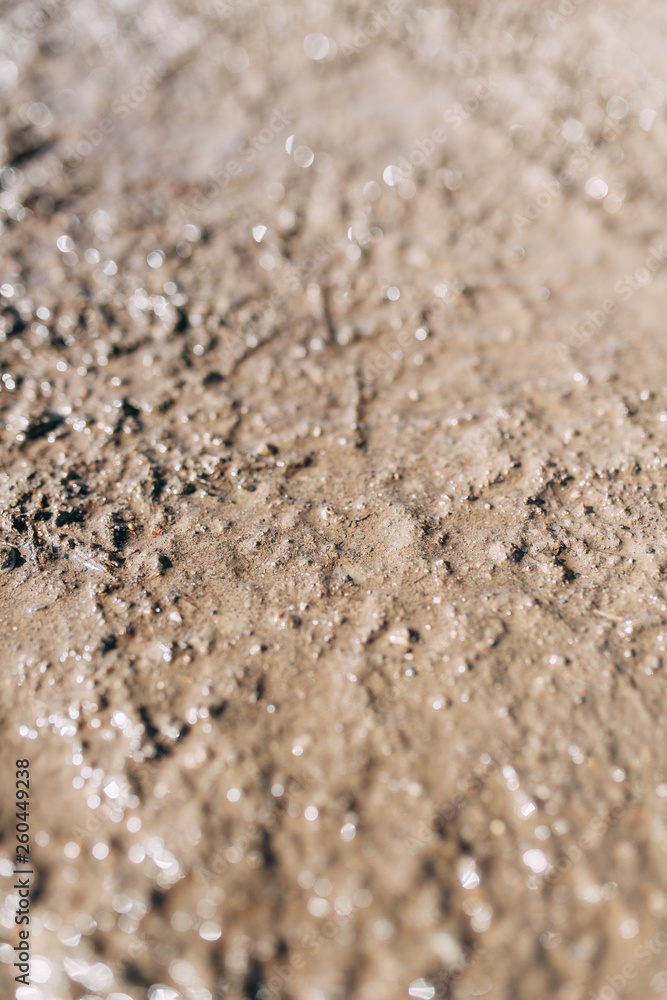 Blurred background and bokeh. The texture of the mud on the ground with a glare. Blurred background and bokeh. The texture of the mud on the ground with a glare.
