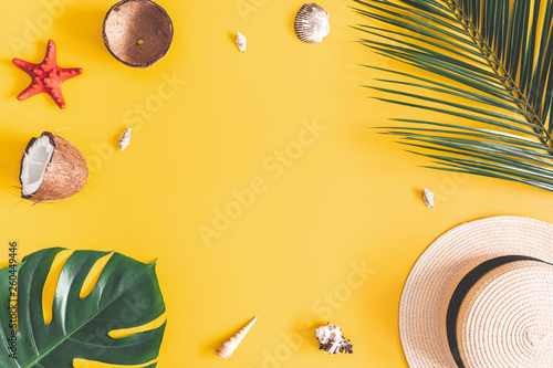 Summer composition. Tropical palm leaves, hat, coconut on yellow background. Summer concept. Flat lay, top view, copy space