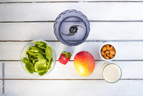 Components of healthy Green Reach Vitamins Smoothie with baby leaf spinach, mango, almond milk and strawberry