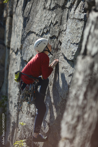 Young woman is engaged in rock climbing in the mountains. Sport climbing.