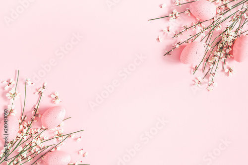 Easter composition. Easter eggs, white flowers on pastel pink background. Flat lay, top view, copy space