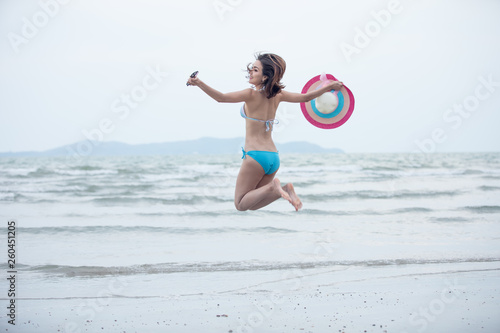 tourist girl in bikini jumping playing relaxation on the sand beach summer holiday concept