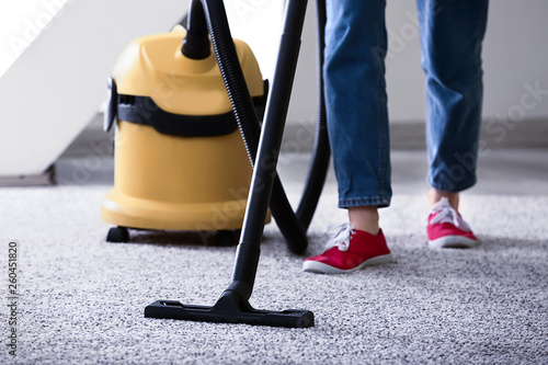 Person vacuuming gray carpe...