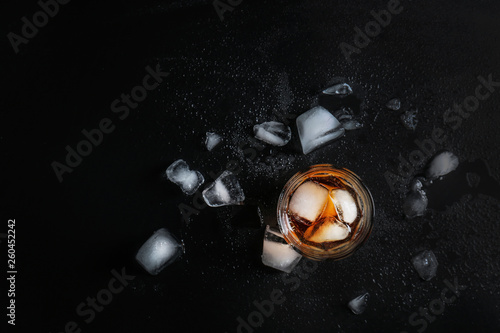 Glass of cold whiskey on dark background