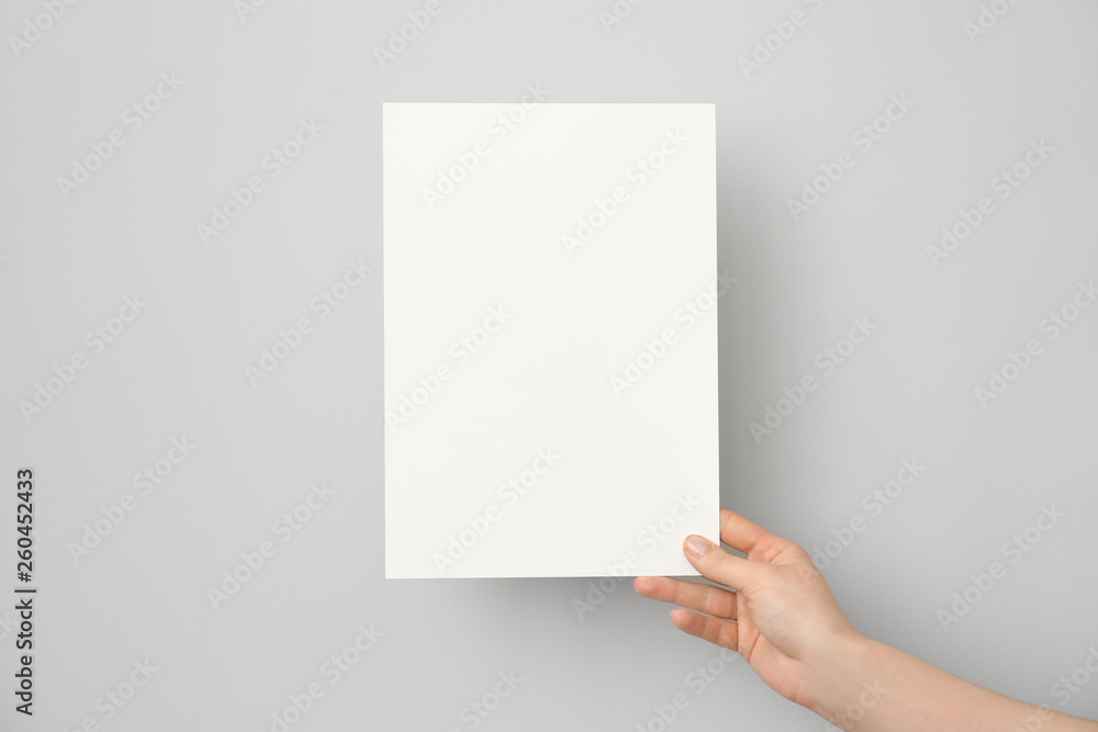 Female hand with blank invitation card on light background Female hand with blank invitation card on light background