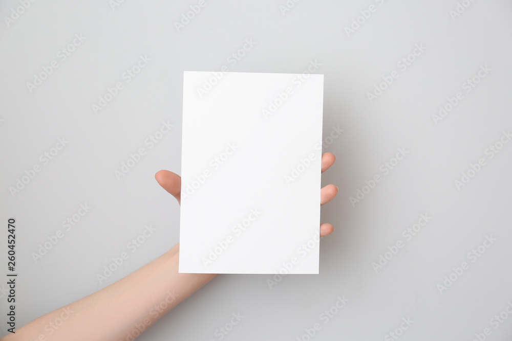 Female hand with blank invitation card on light background Female hand with blank invitation card on light background