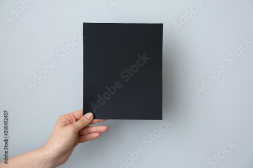 Female hand with blank invitation card on light background