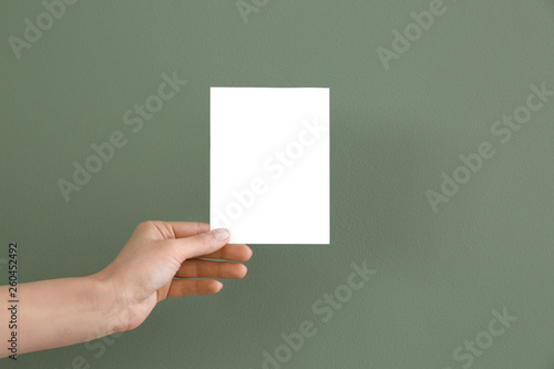 Female hand with blank invitation card on color background