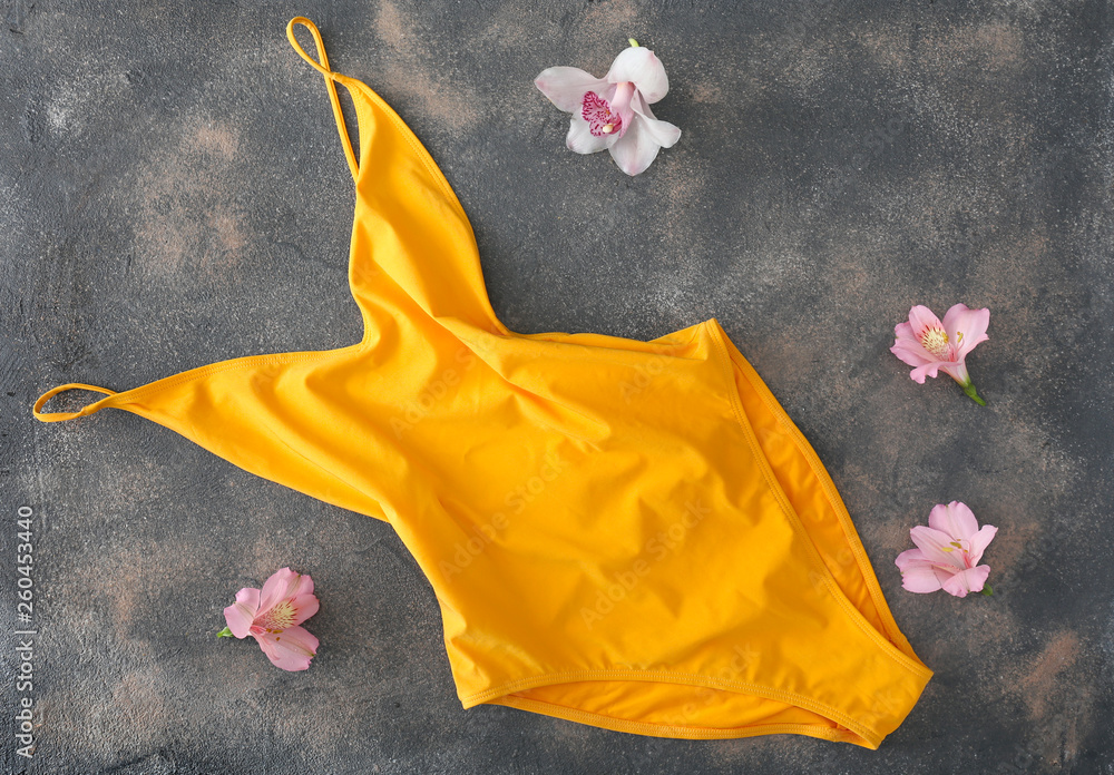 Stylish female swimming suit and flowers on grunge background