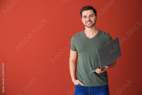 Male programmer with laptop on color background photo