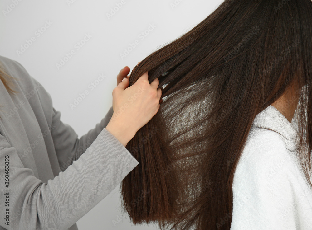 Hairdresser working with long hair of young woman in salon Hairdresser working with long hair of young woman in salon