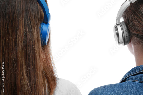 Young women with headphones listening to music on white background