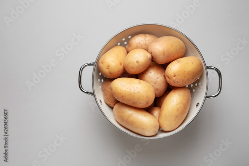 Photos Colander with raw potato on light background