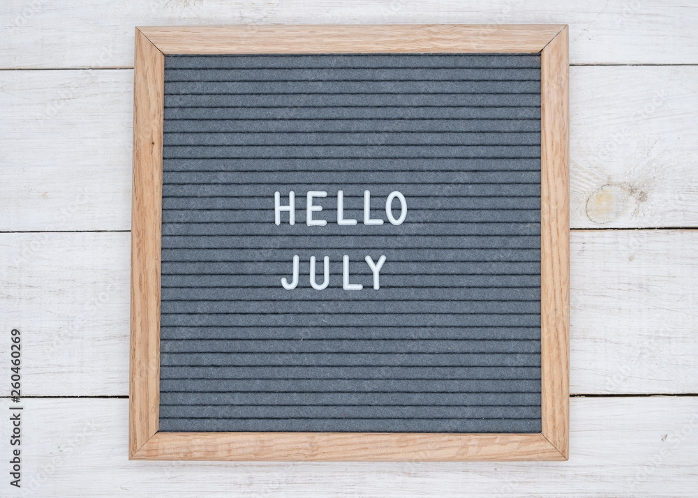 English text Hello July on a letter Board in white letters on a gray background