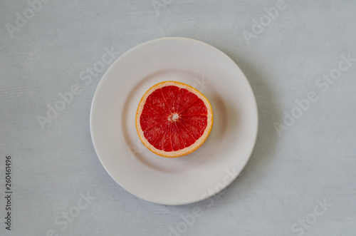 A slice of grapefruit on a white plate.