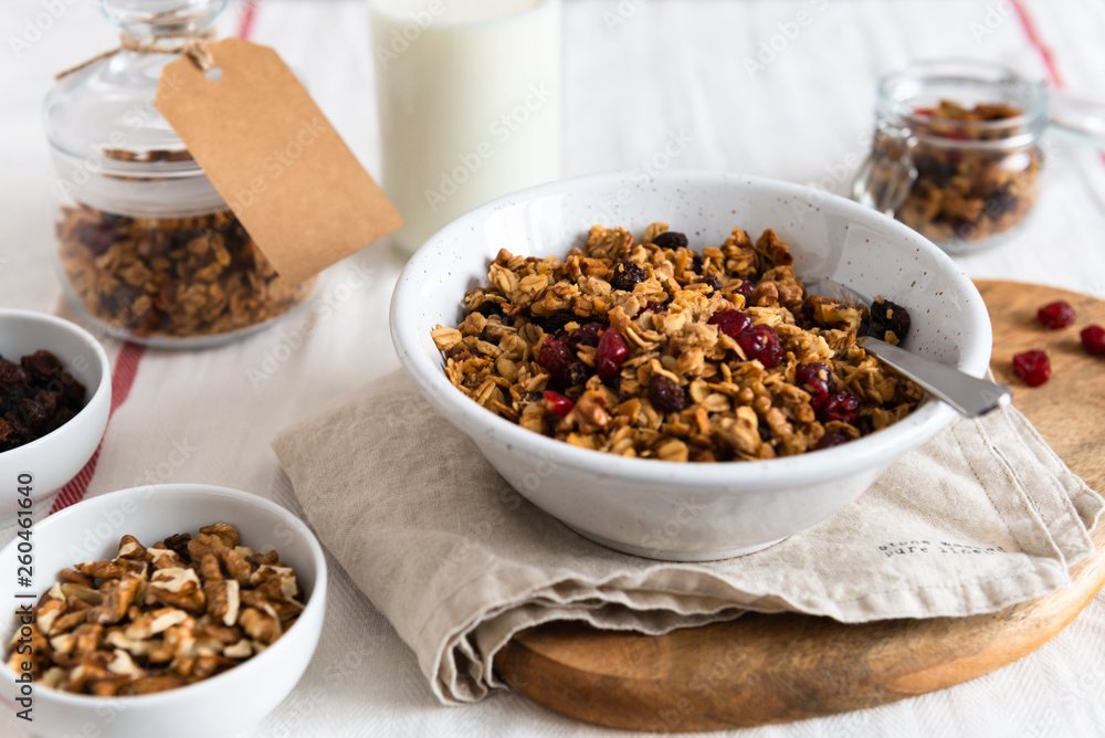 Bowl of homemade granola with nuts and fruits on white linen background. Side view Bowl of homemade granola with nuts and fruits on white linen background. Side view
