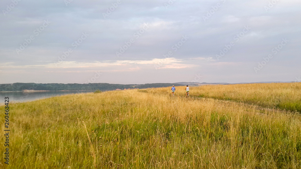 twgirls go by bicycles on the way to the field near the river