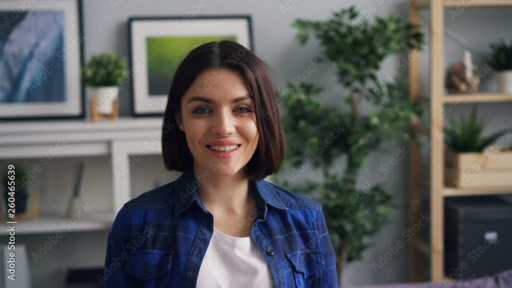 Slow motion portrait of beautiful young woman in modern apartment smiling and looking at camera. Attractive people, positive emotios and youth concept.