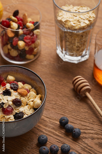 selective focus of cereal in bowl with nuts and dried berries prepared for breakfast