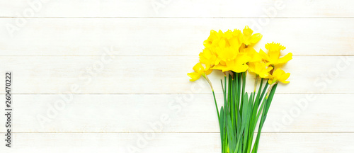 Spring floral background. Yellow narcissus or daffodil flowers on white wooden background top view flat lay. Easter concept, International Women's Day, March 8, holiday. Card with flowers copy space