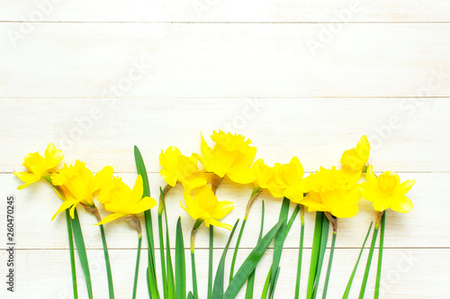 Fototapeta Naklejka Na Ścianę i Meble -  Spring floral background. Yellow narcissus or daffodil flowers on white wooden background top view flat lay. Easter concept, International Women's Day, March 8, holiday. Card with flowers copy space