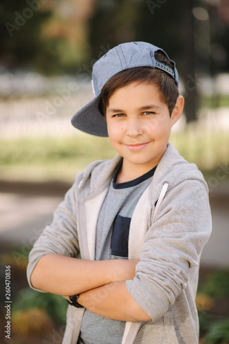 Stylish little school boy in blue cap posing outside for photo. Boy walking in the city in sping summer weather © Aleksandr