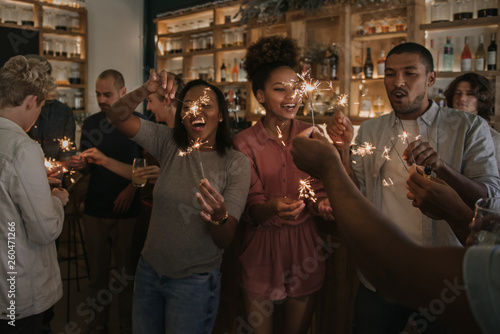 Laughing friends celebrating with sparklers in a bar at night photo