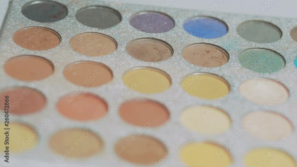 hand of a young girl picks up an eye shadow with a brush from a palette and crushes too much, a woman makes makeup with cosmetics, a beauty concept and a youth lifestyle hand of a young girl picks up an eye shadow with a brush from a palette and crushes too much, a woman makes makeup with cosmetics, a beauty concept and a youth lifestyle