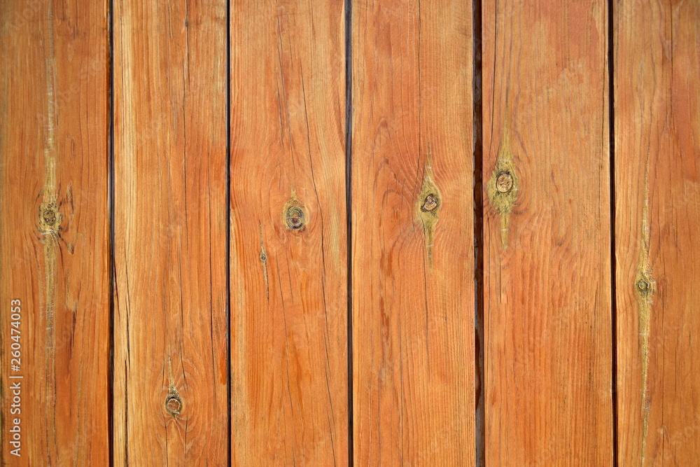 Fototapeta premium A fence from the tightly nailed wooden planks. Natural color of pine wood covered with transparent varnish. Close-up. Selective focus. Copy space. 