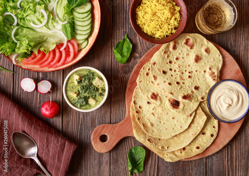 indian vegetarian flat bread chapati with vegetables and hummus on a wooden table top view