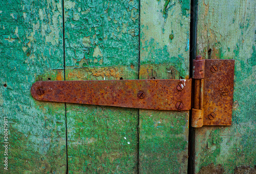 Rusty door hinge on old green wood door with cracked and scratch. Horizontal grunge texture