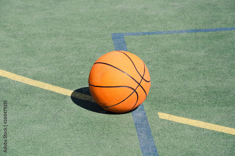 Basketball ball on the rubber sport ground outdoor. Closeup of orange ball on the school playground Basketball ball on the rubber sport ground outdoor. Closeup of orange ball on the school playground