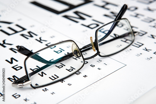 eyeglasses on the table with a font to determine of eyesight Russian version