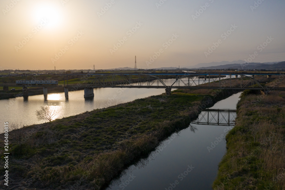 夕暮れの渡良瀬川とローカル列車