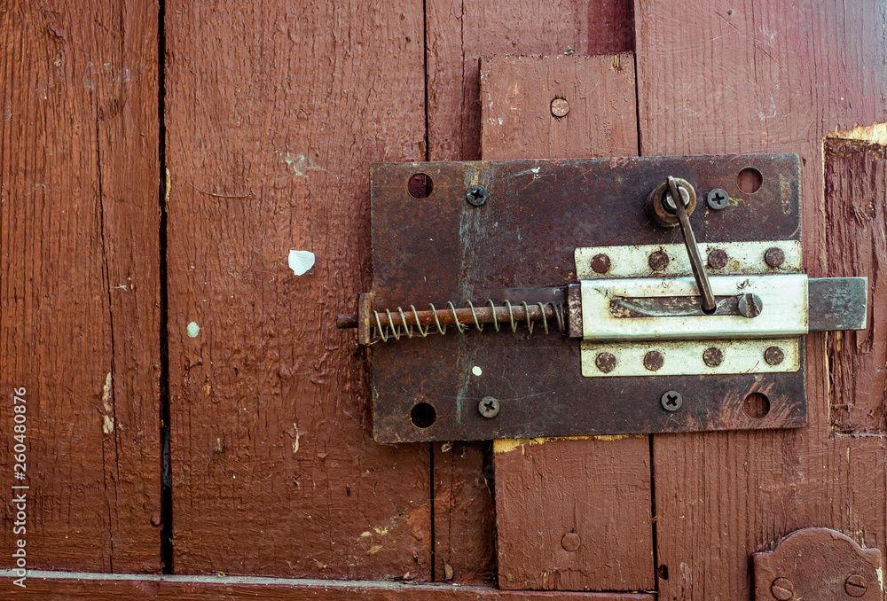 Rusty old secret lock on red wood door with cracked and scratch. Horizontal grunge texture