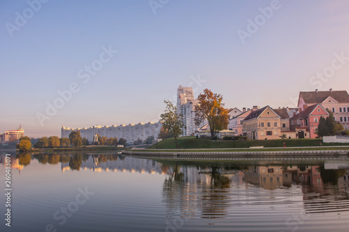 Minsk, Belarus. Pink and lilac dawn. Buildings Trinity suburb and trees are reflected in the river Svisloch.