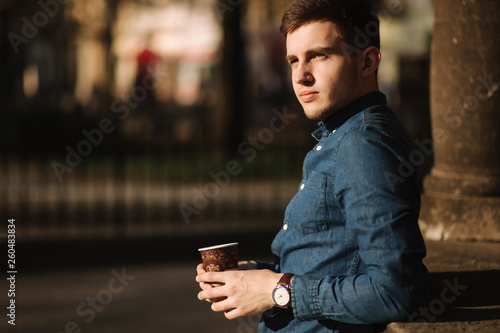 Young boy drink coffee outside. Spring sunset