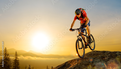 Fototapeta Naklejka Na Ścianę i Meble -  Cyclist in Red Riding the Bike Down the Rock at Sunrise. Extreme Sport and Enduro Biking Concept.