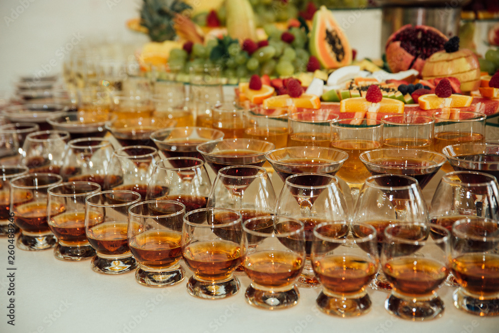stylish glasses with cognac or whiskey on table at wedding reception. alcohol bar. tasty drinks for celebrations and events. luxury stylish catering. christmas and new year feast