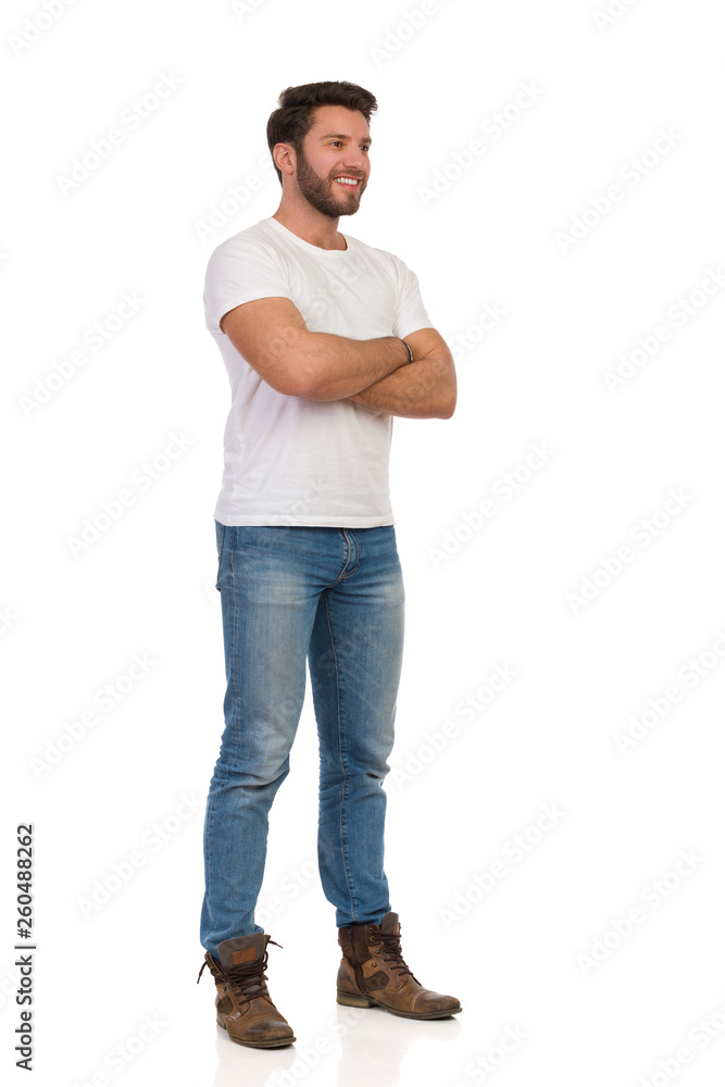 Young Man In Jeans And White T-shirt Is Standing With Arms Crossed And Looking Away Young Man In Jeans And White T-shirt Is Standing With Arms Crossed And Looking Away
