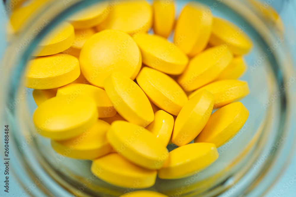 yellow pills spilling out of a toppled pill bottle
