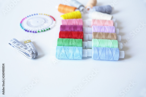 spools of colorful thread  meter and needles on white background. With copy space for text.