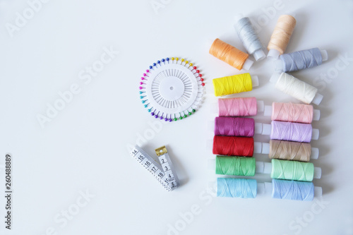 spools of colorful thread, meter and needles on white background with copy space for text