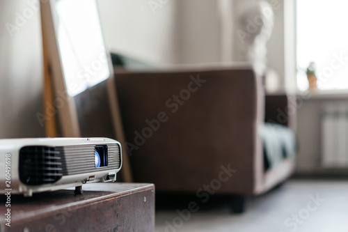 Konstfotografi A digital projector stands on a pedestal in the interior of a teaching class with a sofa and a window in the background